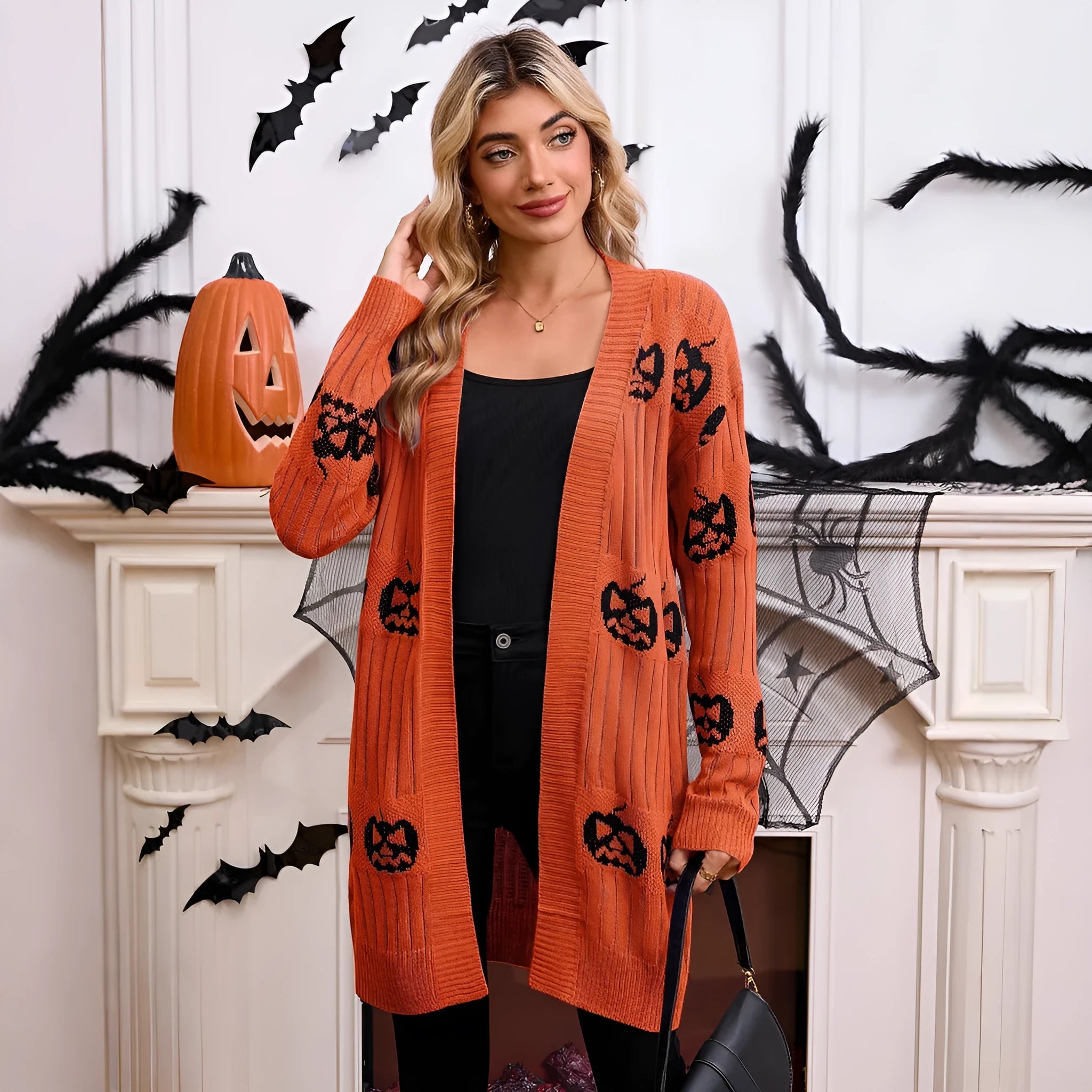Women's black cardigan with orange pumpkin head jacquard knit pattern on the front.