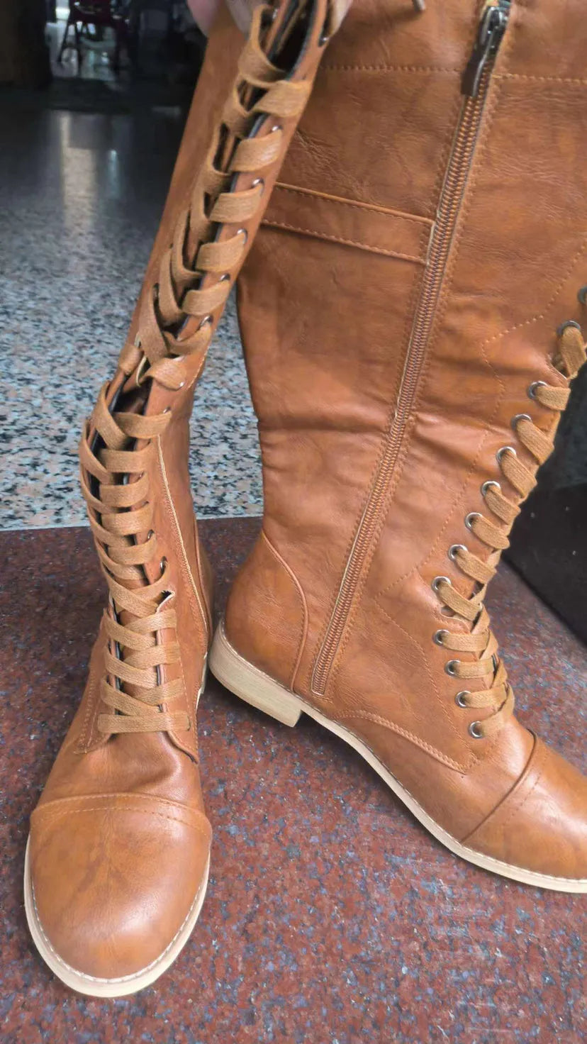 Women's black knight boots with a cross strap design on the shaft.