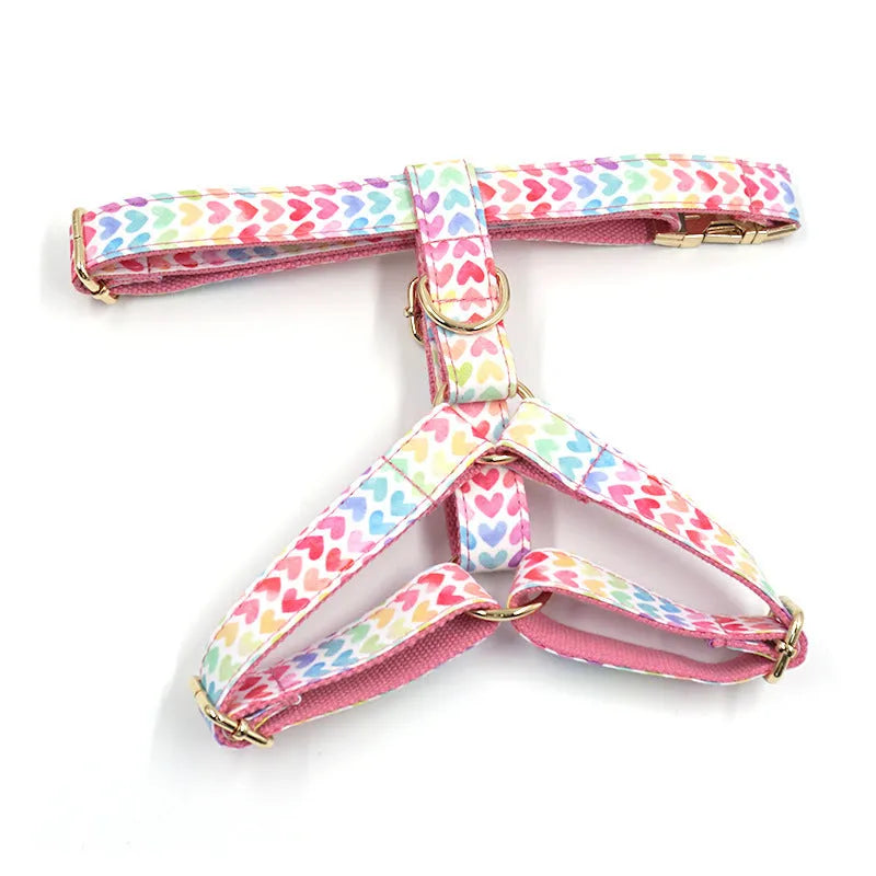 Pink dog harness with a gold buckle and a colourful heart-shaped stone on the chest strap.