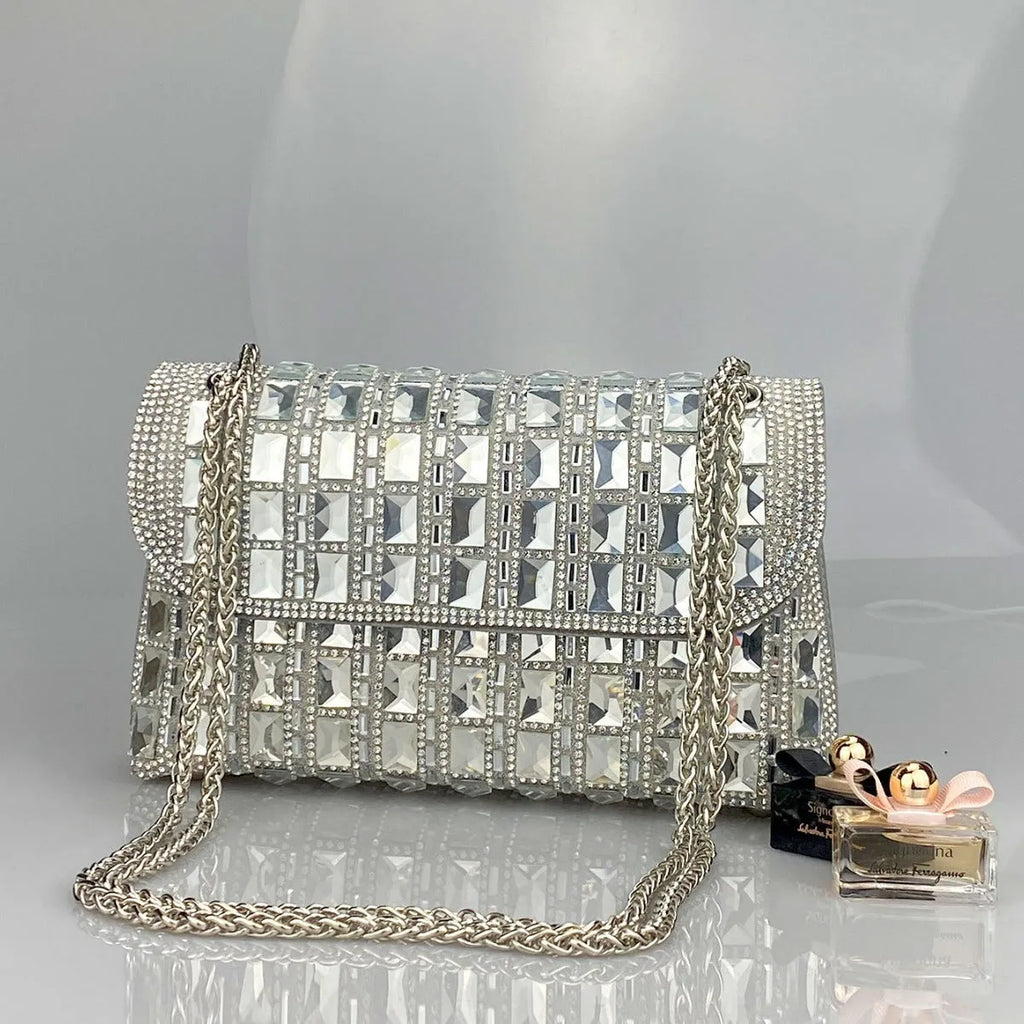 Silver rhinestone chain clutch bag with square shape and internal phone pocket on a table.