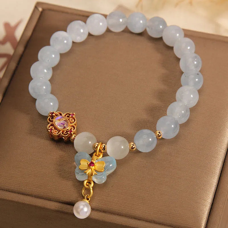 Aquamarine crystal butterfly pendant bracelet for women with rhinestone accents on a white background.