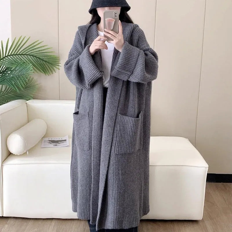 Woman wearing a loose beige hooded zip-front cardigan coat with raglan sleeves.
