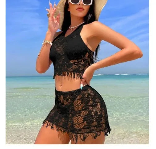 Women's white two-piece bikini with lace cover-up skirt and tassel trim on a beach.