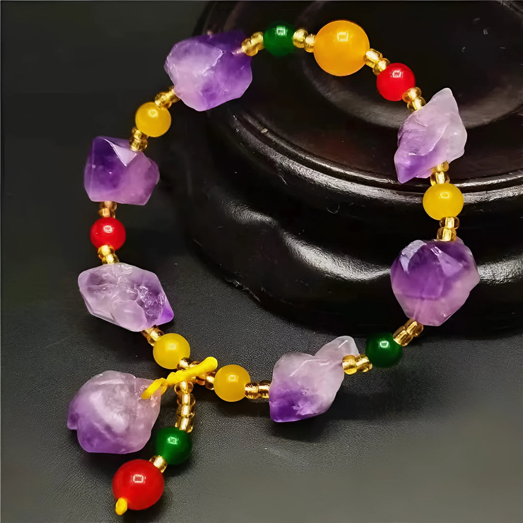 Close-up of a women's bracelet with natural shaped amethyst beads and a silver fu charm on a white background.
