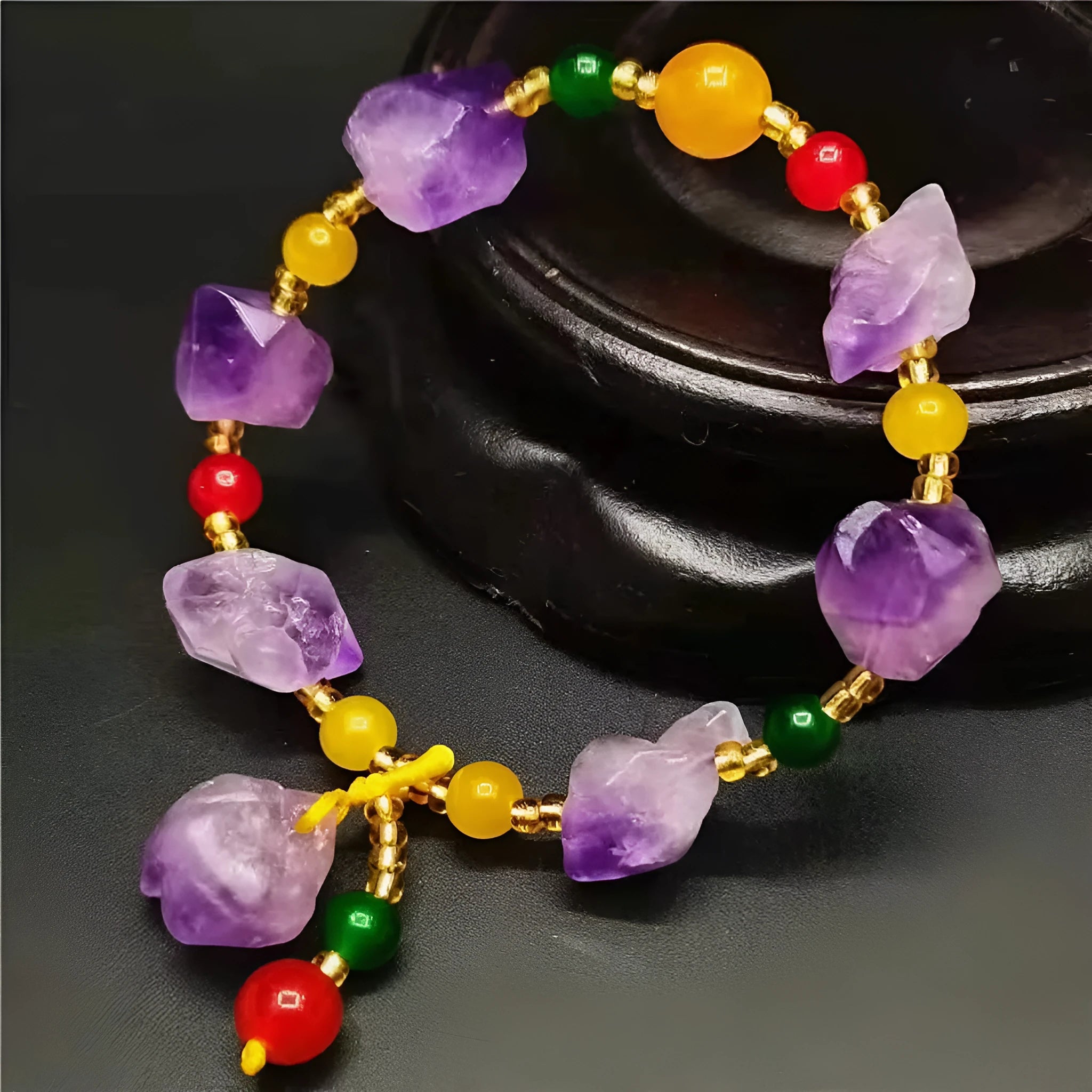Close-up of a women's bracelet with natural shaped amethyst beads and a silver fu charm on a white background.