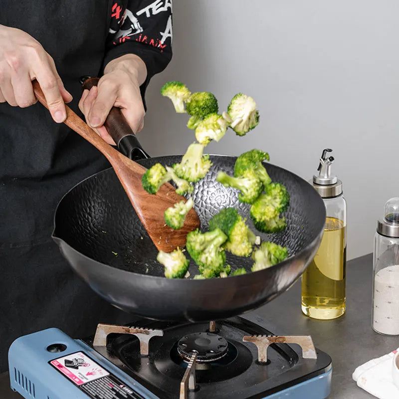 Black traditional iron wok pan with wooden handle and induction base