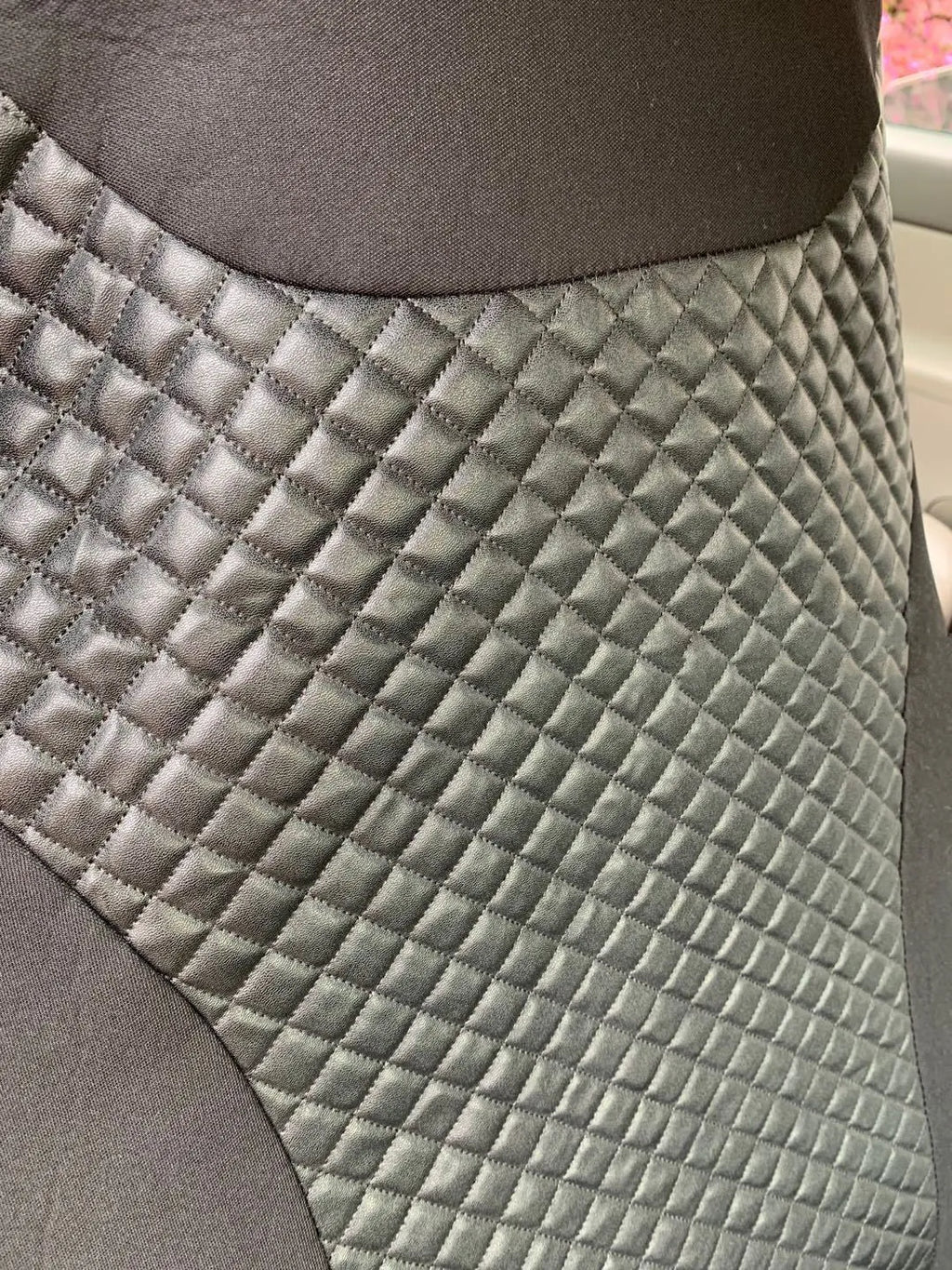 Black quilted automotive seat cover showing dimensional stitching pattern and plastic installation hooks