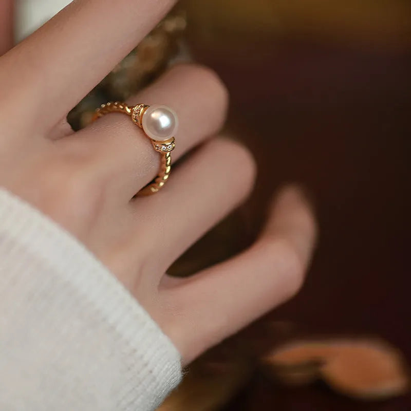 Geometric antique twist ring with a central pearl, on an adjustable copper band in gold colour.