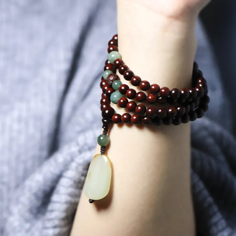 Carved rosewood bead bracelet with Hotian jade pendant showing wood grain texture