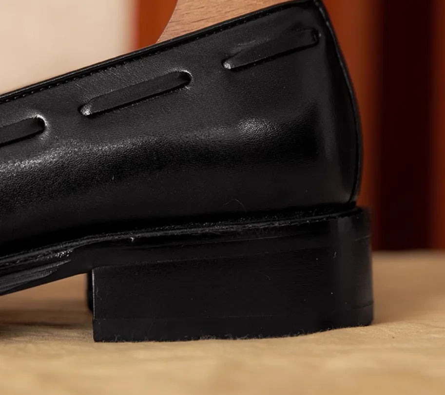 Men's black genuine leather loafers with fringe detail and a rubber sole, shown from a side angle.