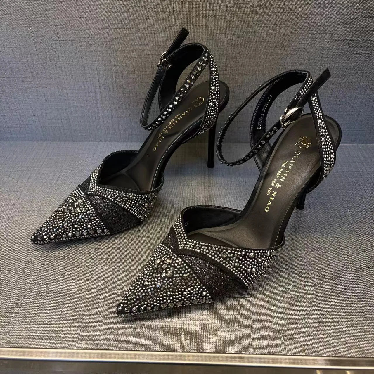 Women's black pointed toe stiletto heels with a hollow design and red sole.