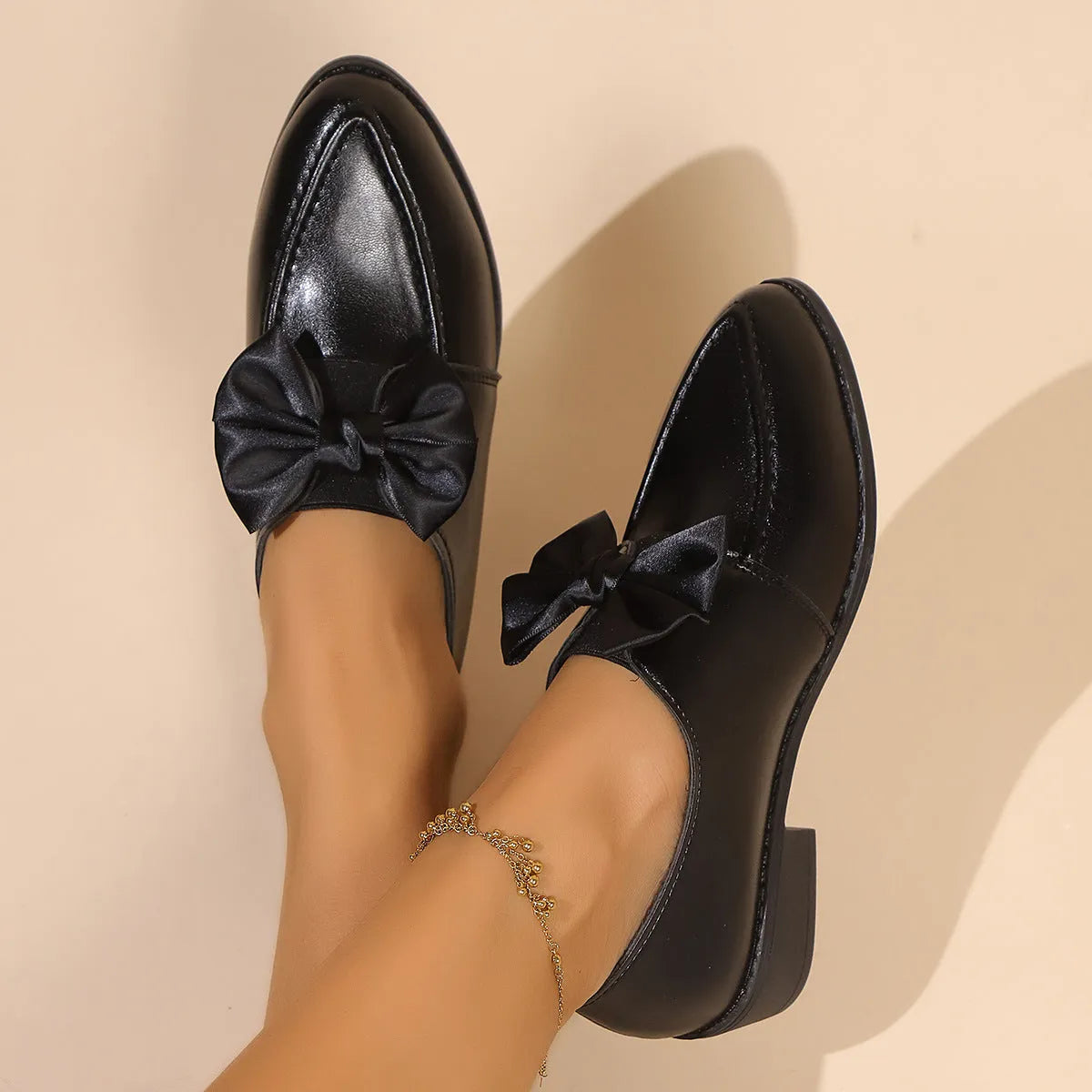 Women's beige PU leather slip-on shoes with a large bow decoration and rubber sole.