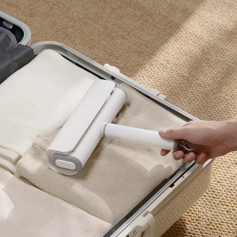 Reusable plastic lint remover roller with a long adhesive paper roll for pet hair and dust on floors.
