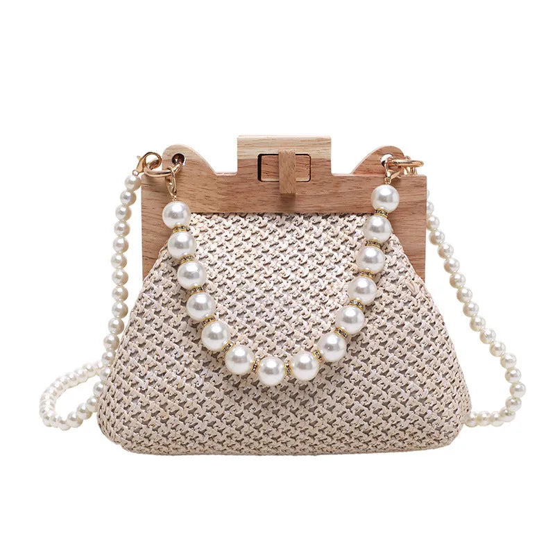 Women's woven straw shoulder bag with pearl chain detail showing horizontal square shape and internal compartments