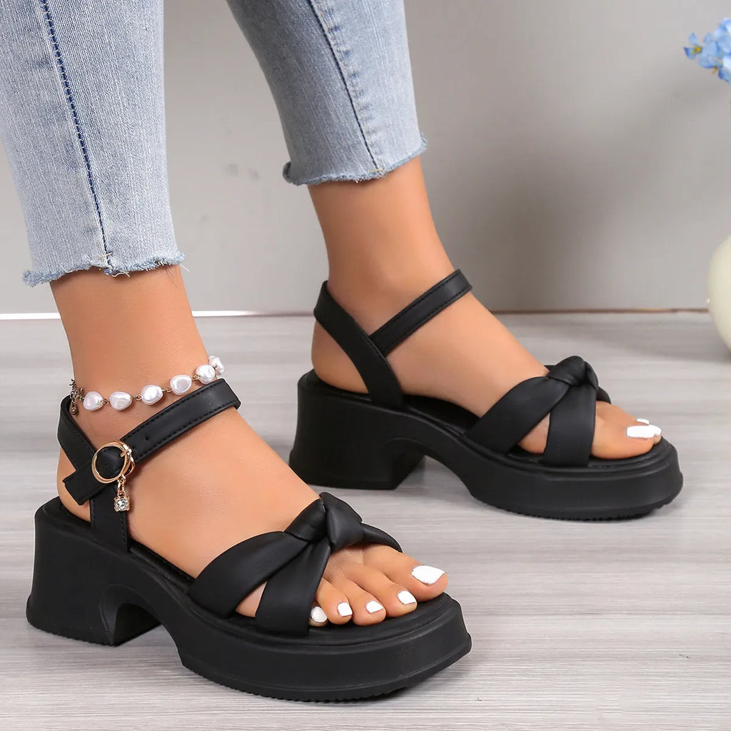 Black high-heel slippers with a thick rubber sole and a button fastening over the instep.