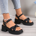 Black high-heel slippers with a thick rubber sole and a button fastening over the instep.
