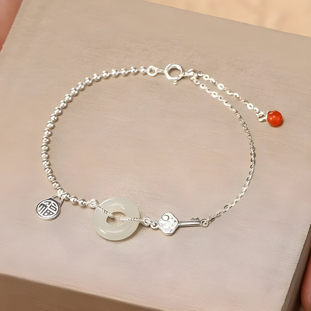 Women's silver bracelet with Hetian jade and a traditional Chinese peace buckle charm on a geometric link chain.