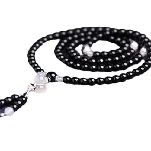 Black agate bracelet with 108 geometric beads on a wrist.