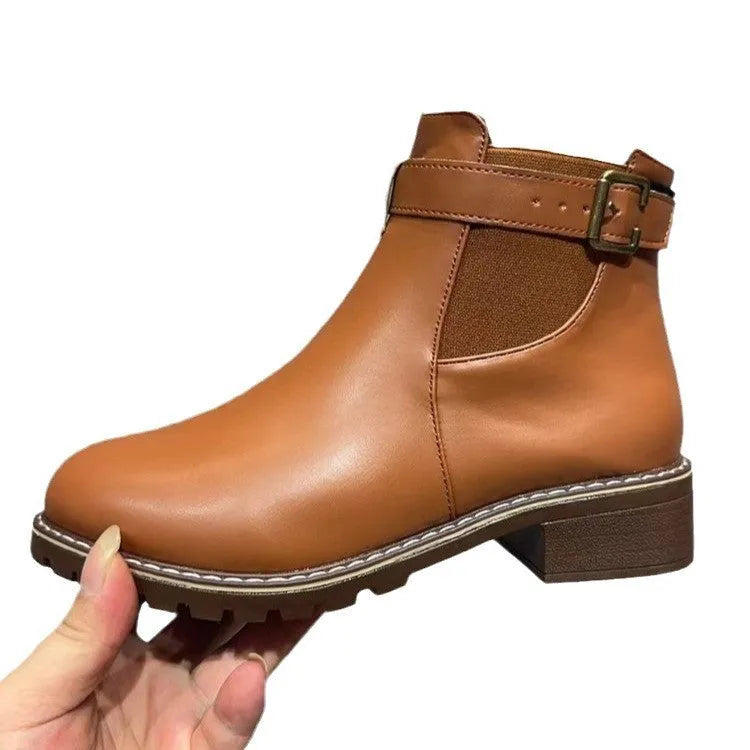 Black round toe ankle boot with a silver belt buckle decoration on the side.