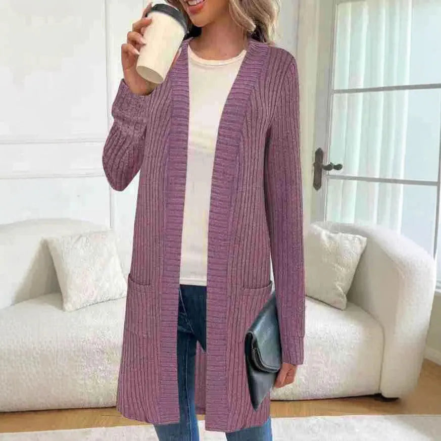 A woman wearing a loose grey knitted cardigan jacket with long sleeves and patch pockets.