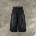 Man wearing black cropped denim shorts with a flame embroidery patch on the leg, street style.