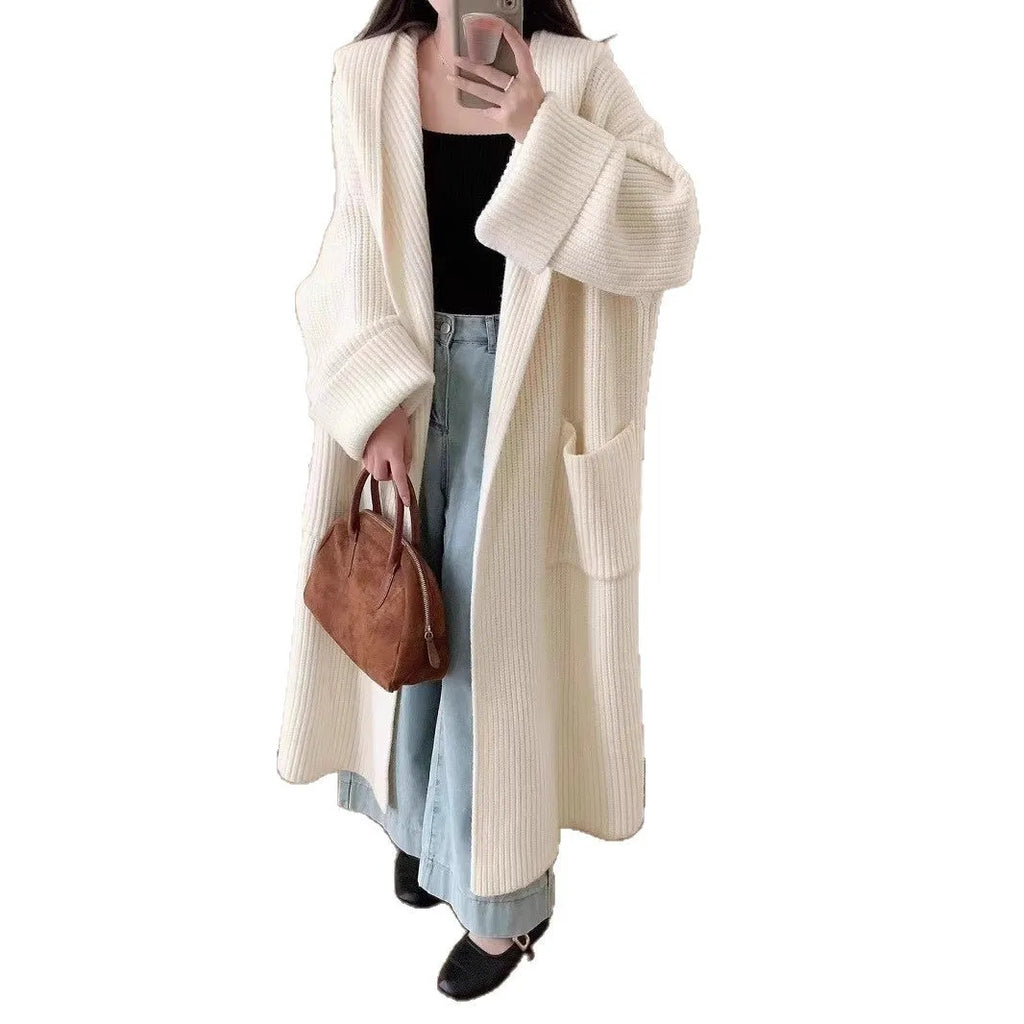 Woman wearing a loose beige hooded zip-front cardigan coat with raglan sleeves.