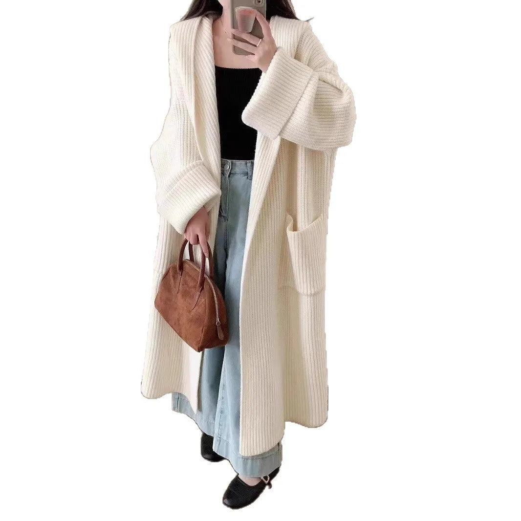Woman wearing a loose beige hooded zip-front cardigan coat with raglan sleeves.