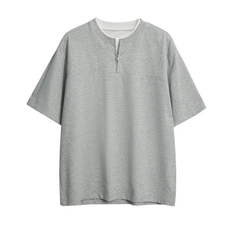 A loose blue cotton blend pullover top with a false zip and patchwork collage stitching detail.