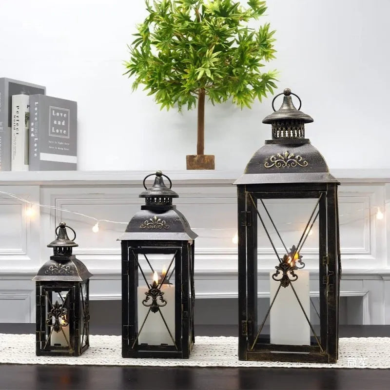 Wrought iron floor-standing storm lantern with tempered glass panels in black gold brushed finish.