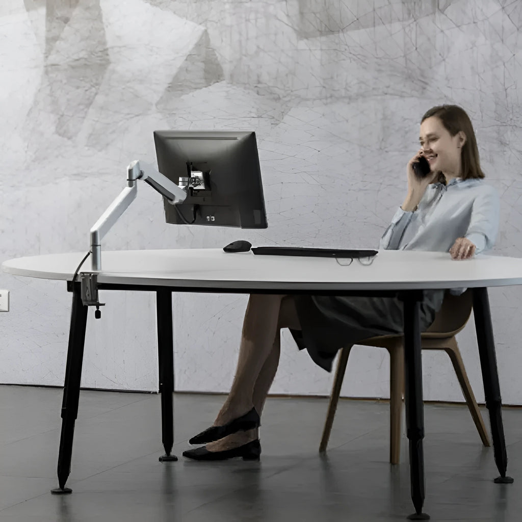 Silver aluminium Free Hover adjustable laptop and monitor arm bracket extended on a desk.