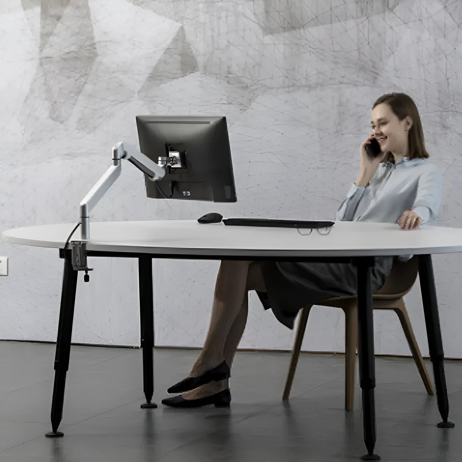 Silver aluminium Free Hover adjustable laptop and monitor arm bracket extended on a desk.