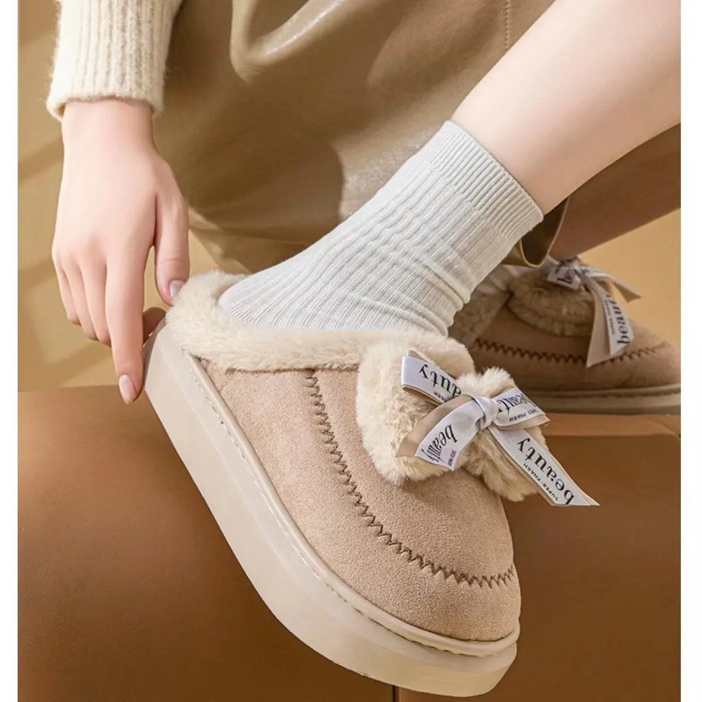 Women's beige suede half slippers with a thick sole and wool lining on a wooden floor.