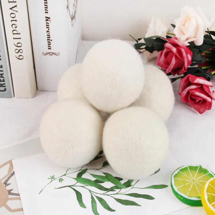 Handmade natural wool felt drying ball for laundry next to a plain cotton storage bag.