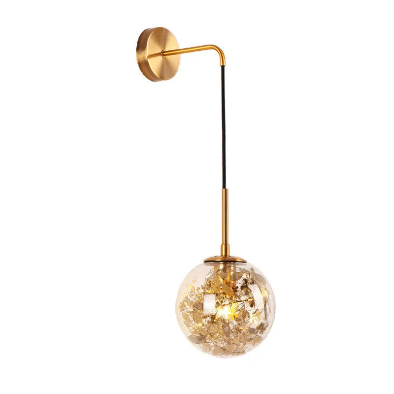 Modern round glass wall lamp in golden flower finish mounted beside a bed.