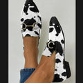 Women's black and white cow pattern pointed-toe mules with flat square heel on a neutral background