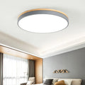 Round Nordic style wooden and iron LED ceiling lamp on a white ceiling.