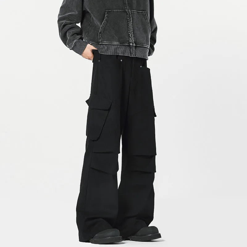 Men's black high-waisted straight-leg trousers with a button fly front, laid flat on a grey background.