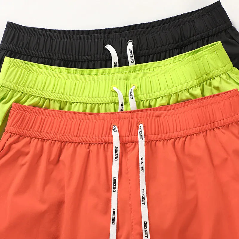 Men's loose orange red polyester beach surfing shorts with elasticated waist on a man