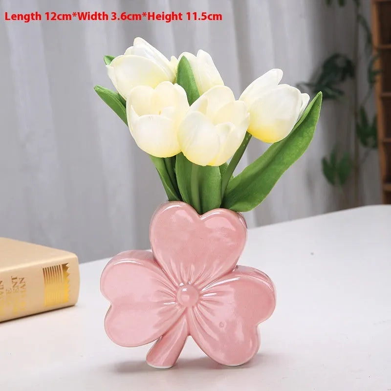 White porcelain clover-shaped ceramic vase on a desk, shown in light green colour.