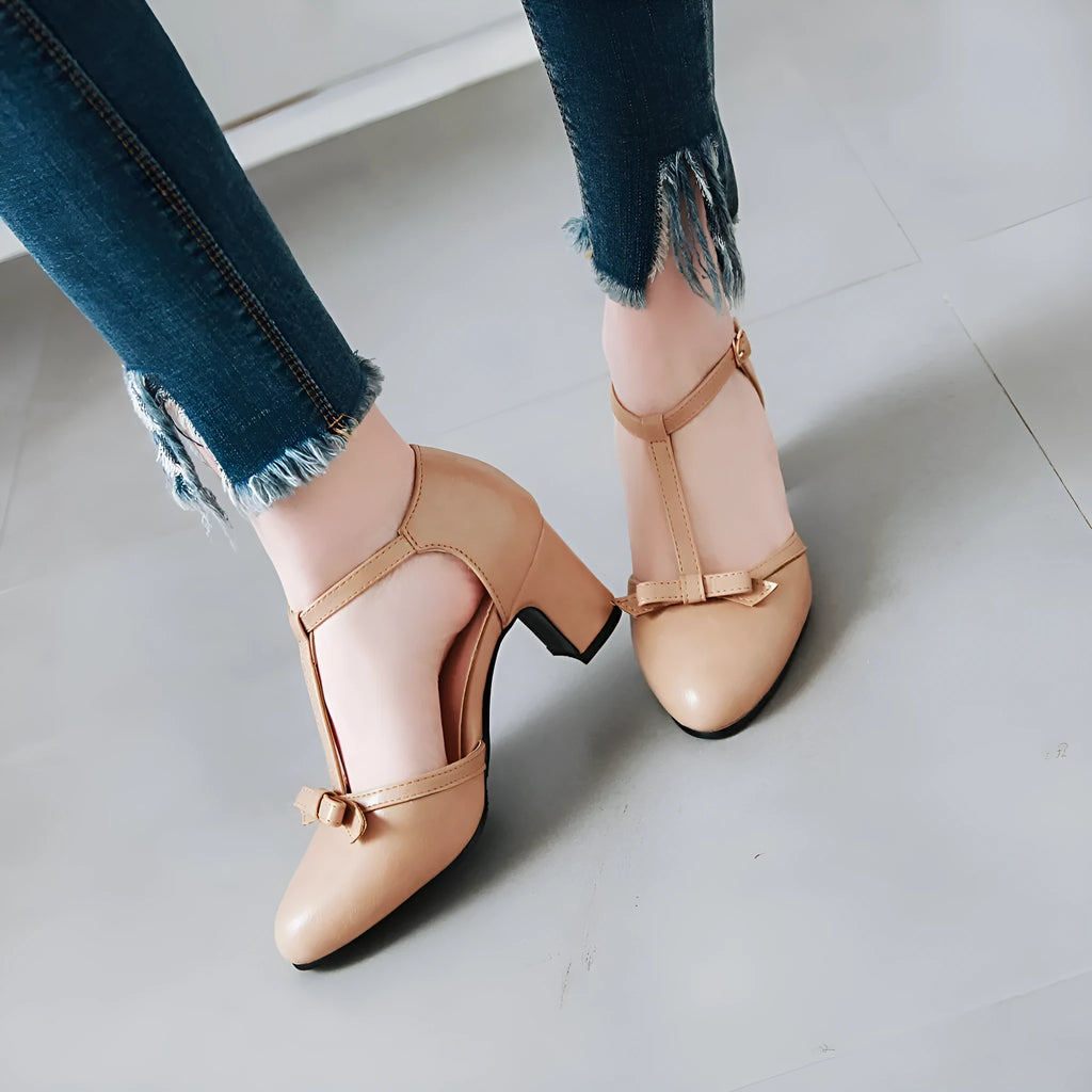 Women's apricot coloured sandals with a chunky heel, buckle strap, and bow detail on the toe.