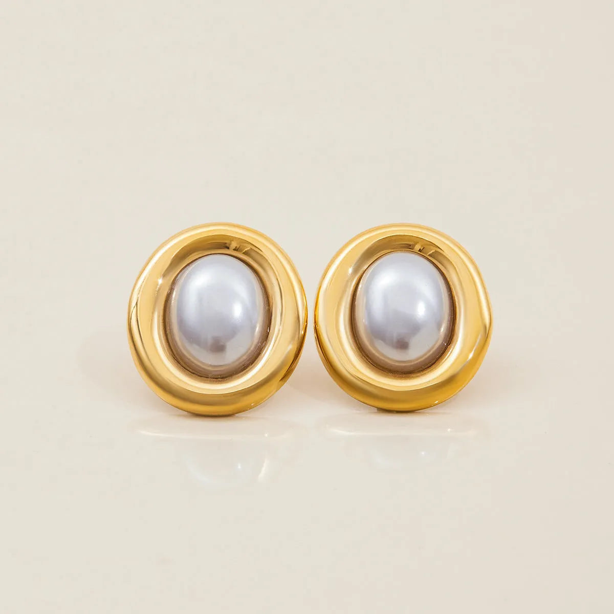A pair of stainless steel stud earrings with a small vintage-style pearl drop and a non-fade electroplated finish.