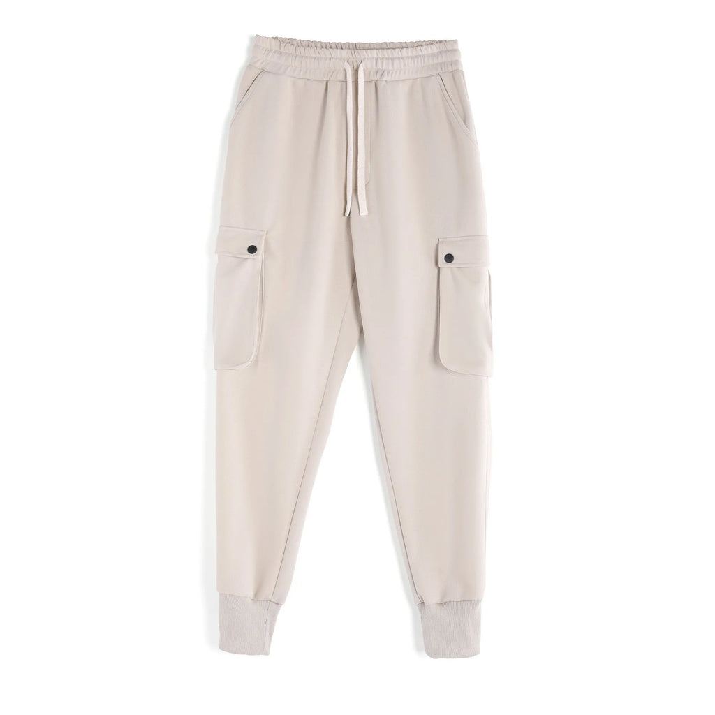 Man wearing loose light grey cotton sports trousers with ankle ties and multiple pockets.