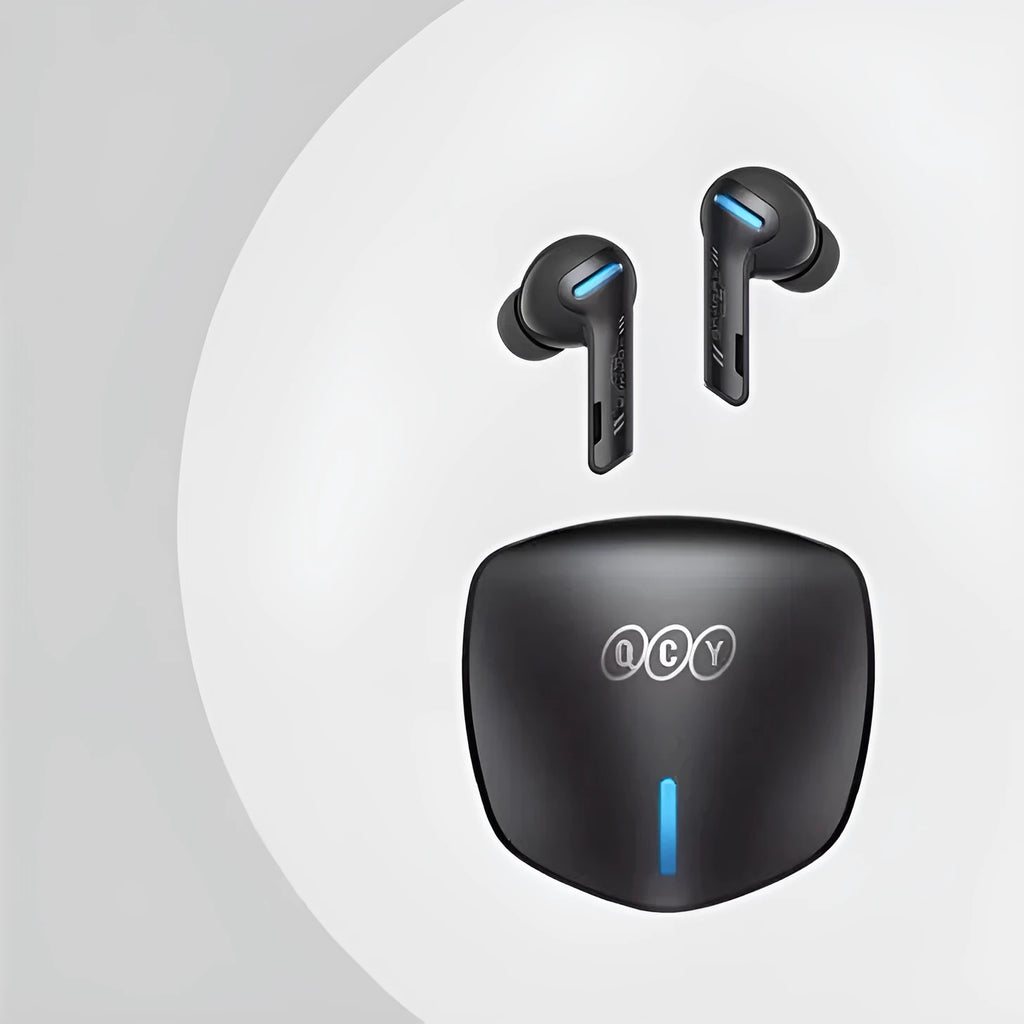 Grey QCY-G1 wireless Bluetooth gaming headset with charging case and ear tips on a table.