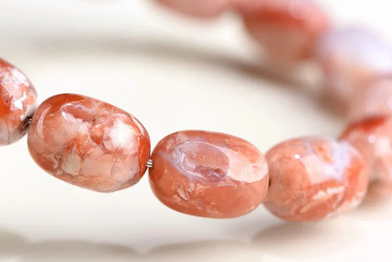 Natural cherry agate barrel bead bracelet with Ruyi charm showing 10x14mm beads