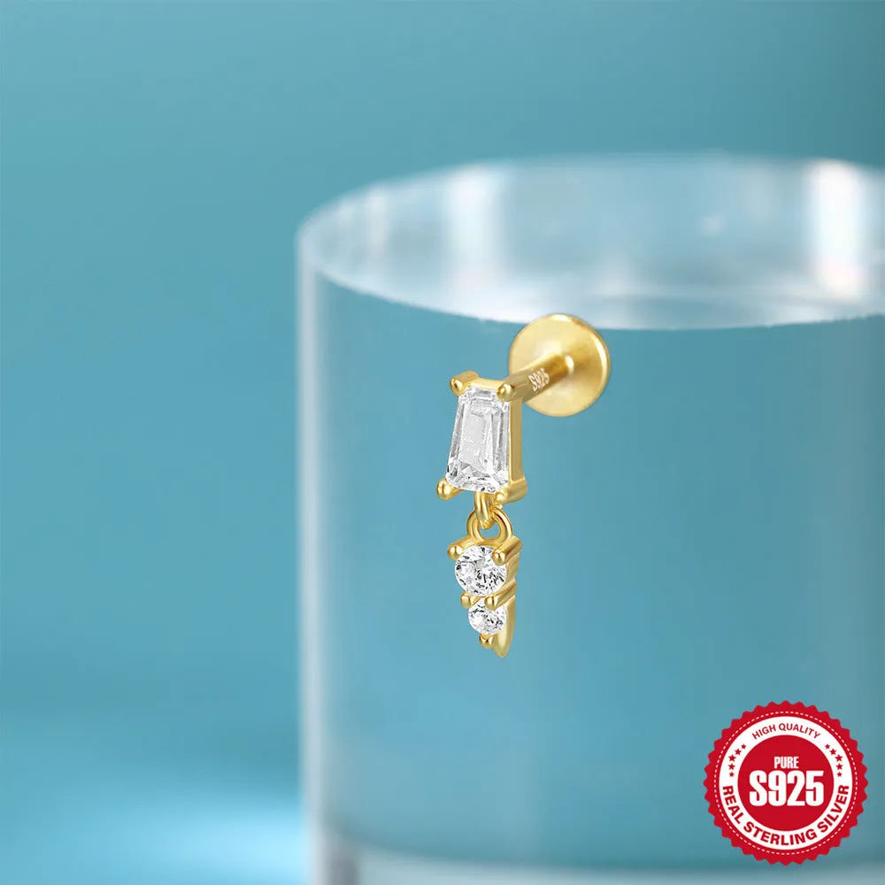 Close-up of a sterling silver ear stud with a gold-toned tassel inlay design.