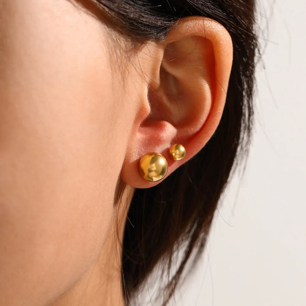 Simple stainless steel stud earrings with geometric sphere design in gold colour on white background