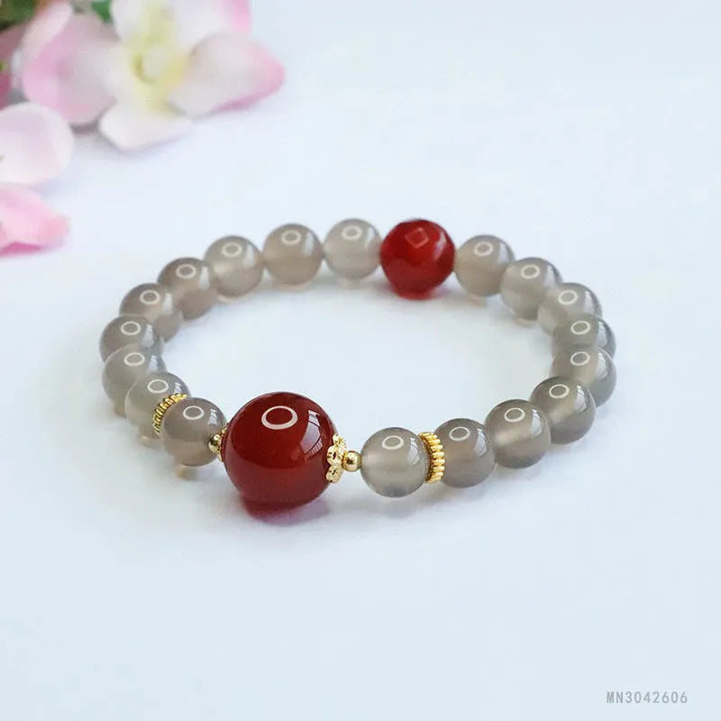 Close-up of a bracelet with smoky purple and red agate geometric beads on a white background.