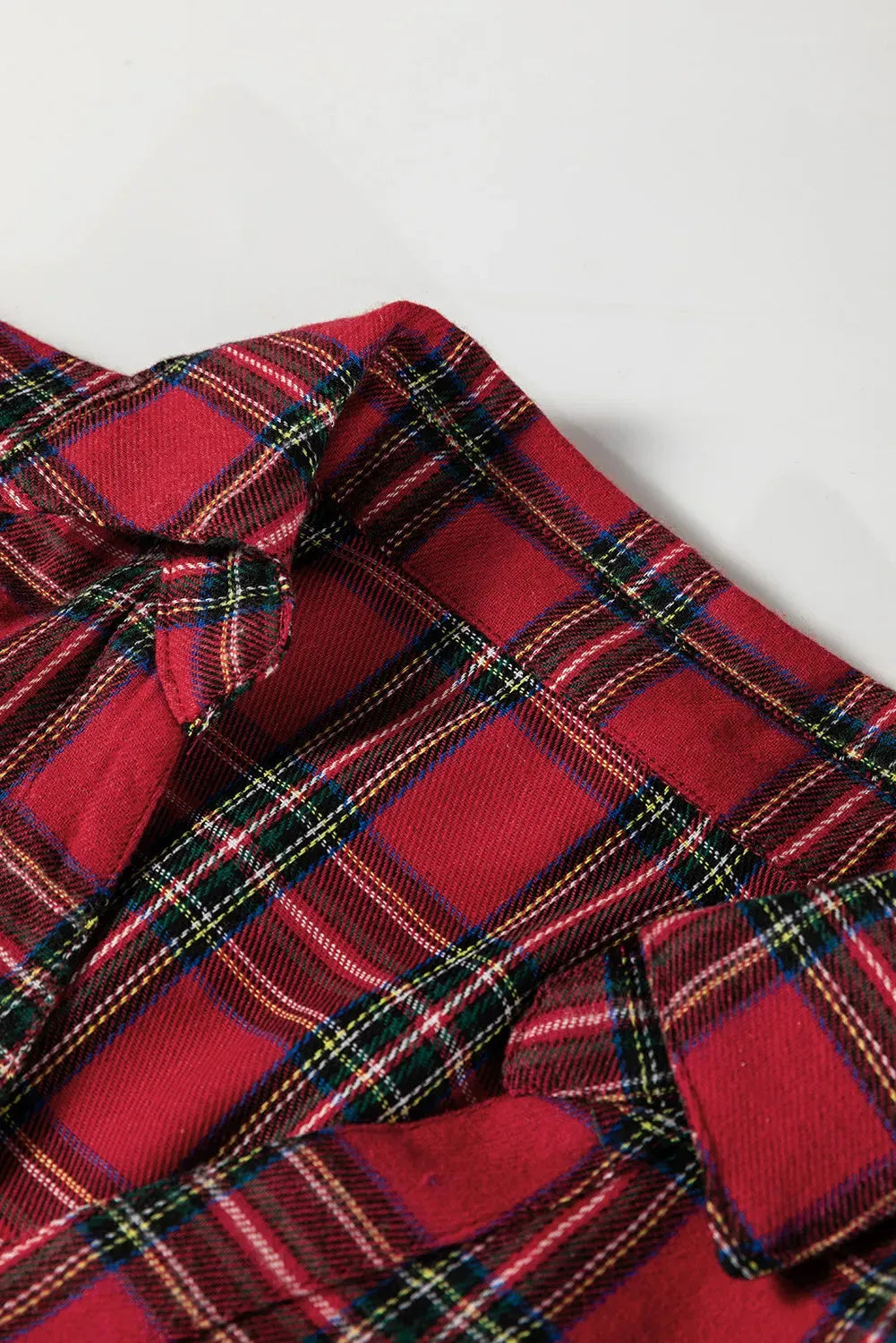 Red and black plaid women's mini dress with a shirt collar, half-button front, long sleeves, and a ruffle hem.