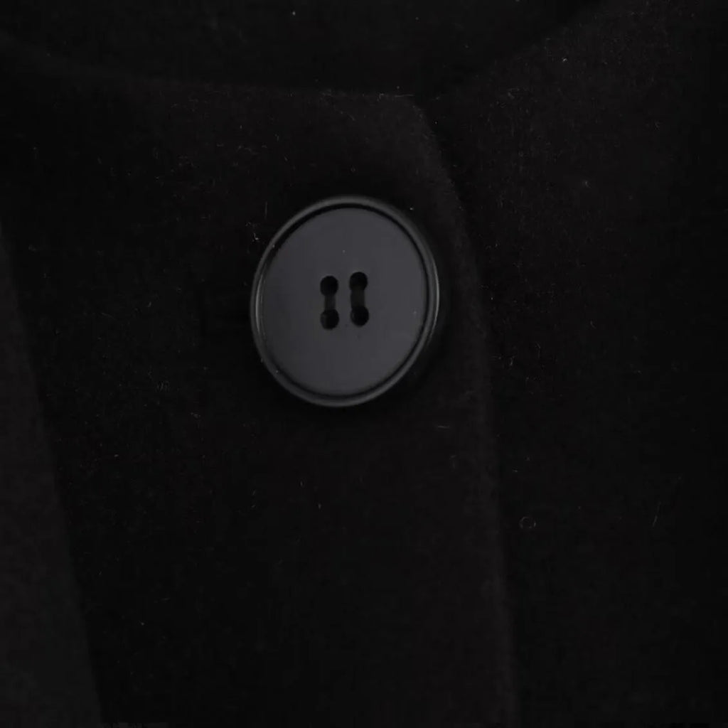 Woman wearing a long black overcoat with a detachable artificial fur collar, styled in a street-fashion look.