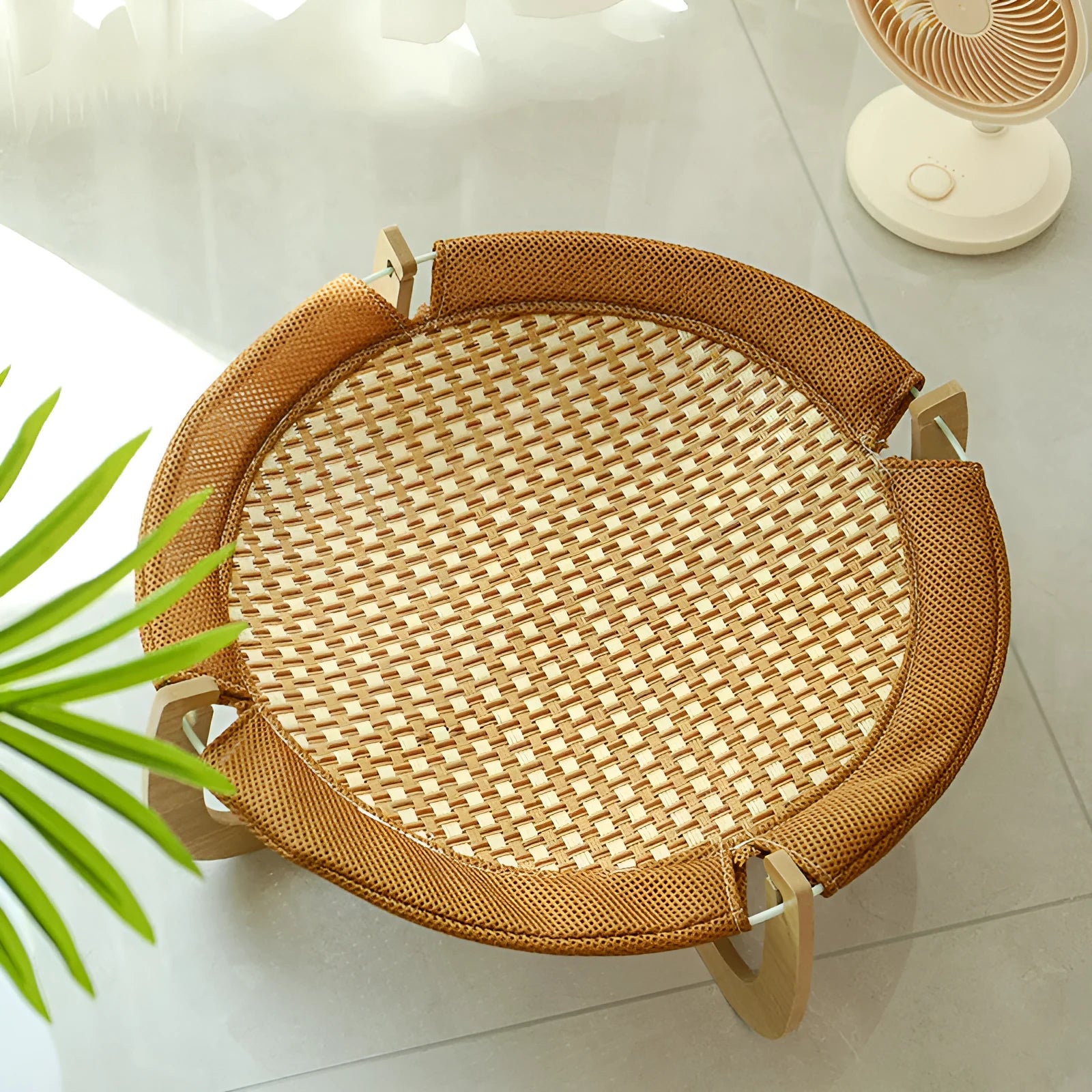 Brown woven rattan raised cot bed for cats and small dogs on a wooden floor